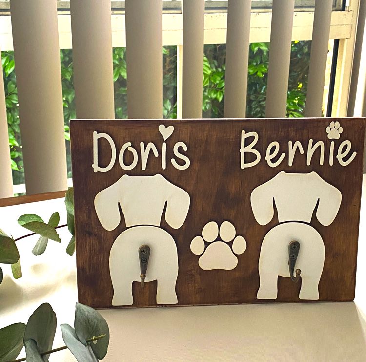 Double Dog Leash Holder in Timber with white names and dog butt silhouettes.