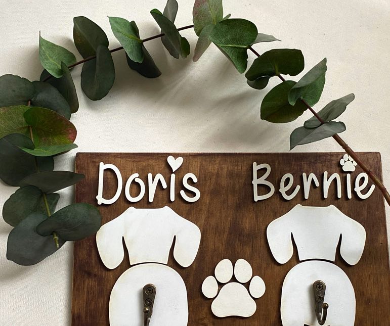 Double Dog Leash Holder in Timber with white names and dog butt silhouettes.