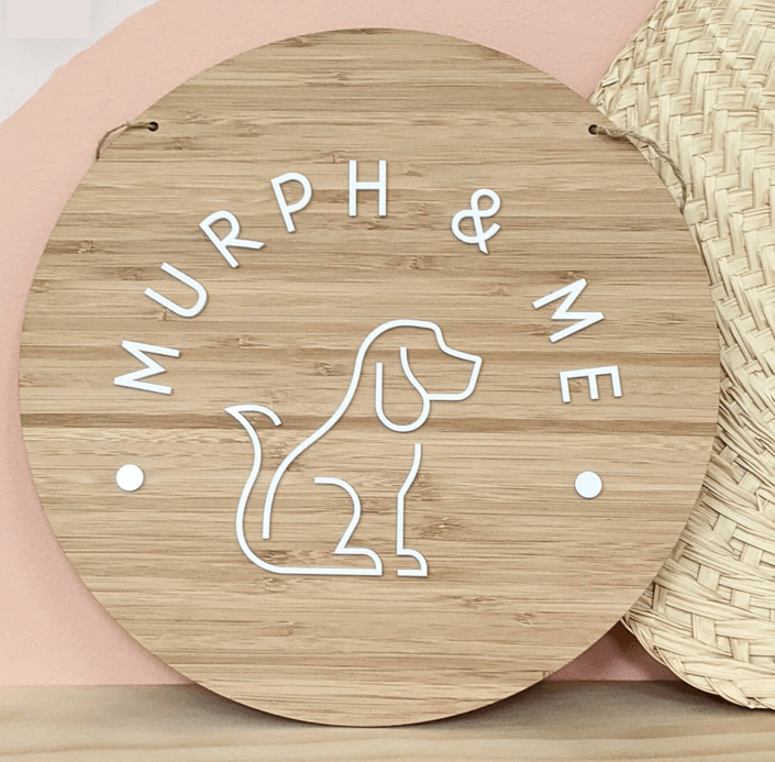 Round plywood wall plaque of a dog sitting with Murph and Me in a half circle above dog outline. Bubs and bobbins laser cut designs for dogs
