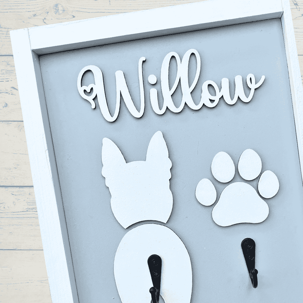 Close up framed Dog Leash/Harness Holder in Hampton style hand painted in grey background and white frame, white dog’s name with white paw print plus 2 hooks. 