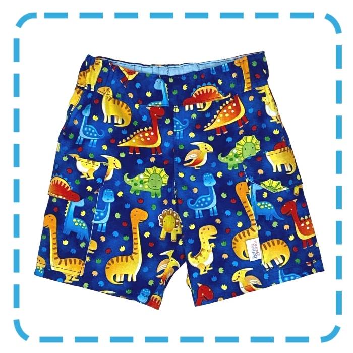 Little Boy's shorts with colourful dinosaurs all over the fabric.  The cargo shorts have large pockets with flaps.  They are sold in a ready to SEW kit or made for you by Bubs & Bobbins.