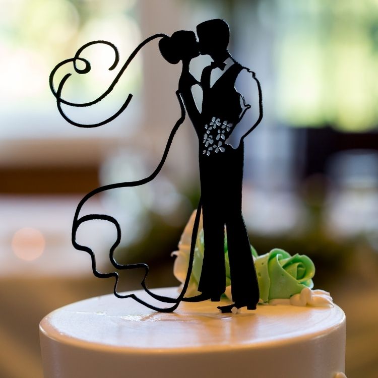 Photo of a wedding cake  with a cake topper on top of the cake showing a silhouette of a bride and groom  dancing.  This is available from Bubs & Bobbins.